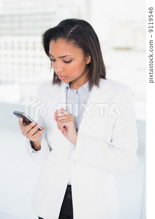 Thinking young dark haired businesswoman looking at her mobile p Thinking young dark haired businesswoman looking at her mobile p 9119546