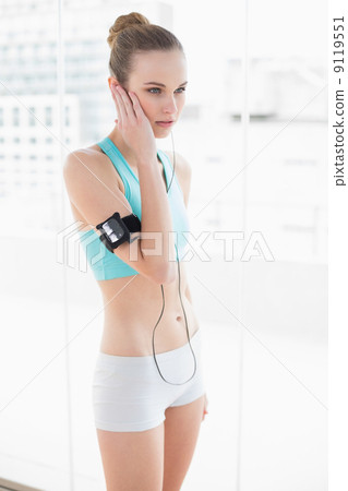 Sporty stern woman listening to music Sporty stern woman listening to music 9119551