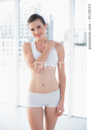 Smiling fit brown haired model in sportswear posing with a hand 9119553