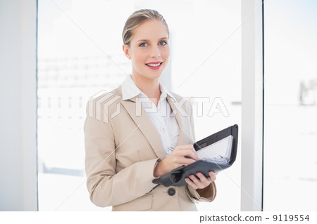 Smiling blonde businesswoman writing on datebook Smiling blonde businesswoman writing on datebook 9119554