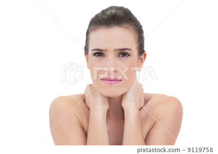 Frowning natural brown haired model holding her neck 9119758