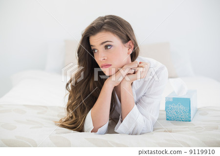 Beautiful casual brown haired woman in white pajamas lying on he 9119910