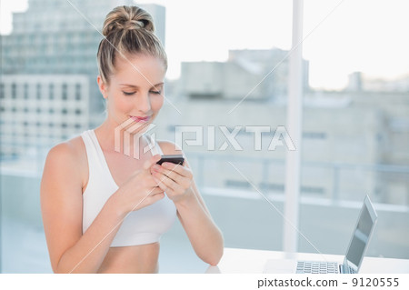 Smiling sporty blonde sending a text 9120555