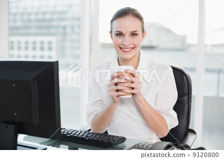Businesswoman holding disposable cup smiling at camera 9120800