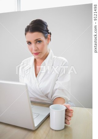 Charming businesswoman working on laptop 9121498