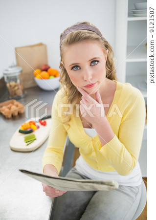 Pensive cute blonde holding newspaper 9121507