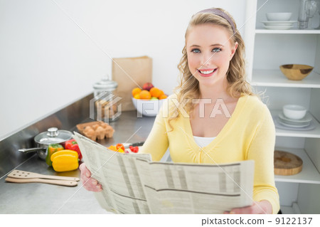 Smiling cute blonde holding newspaper Smiling cute blonde holding newspaper 9122137