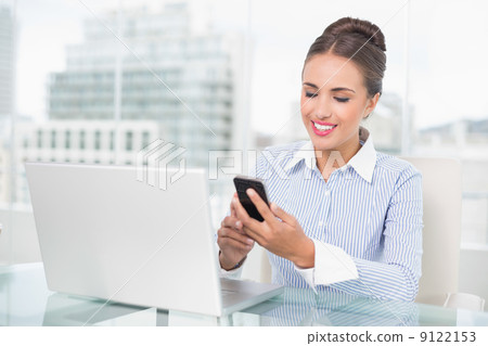 Smiling brunette businesswoman looking at smartphone Smiling brunette businesswoman looking at smartphone 9122153
