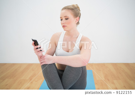 Attractive sporty blonde looking at smartphone Attractive sporty blonde looking at smartphone 9122155