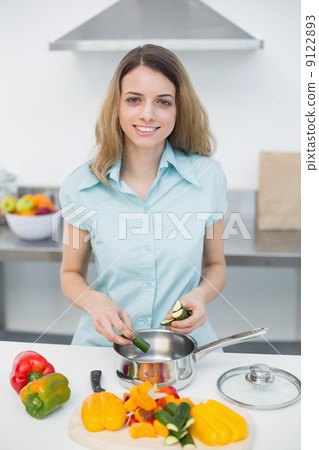 Sweet smiling woman cutting vegetables standing in kitchen 9122893