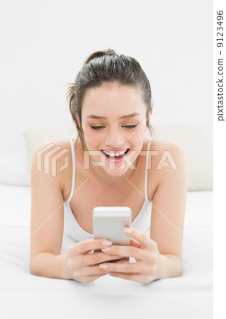 Happy casual woman looking at mobile phone in bed 9123496