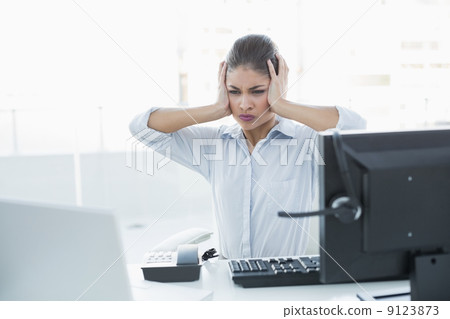 Businesswoman suffering from headache in front of computer 9123873