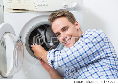 Smiling technician repairing a washing machine Smiling technician repairing a washing machine 9123904