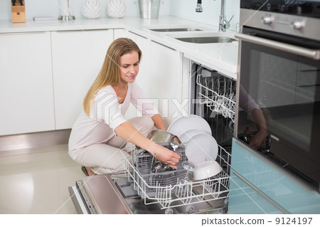 Happy gorgeous model kneeling behind dish washer 9124197