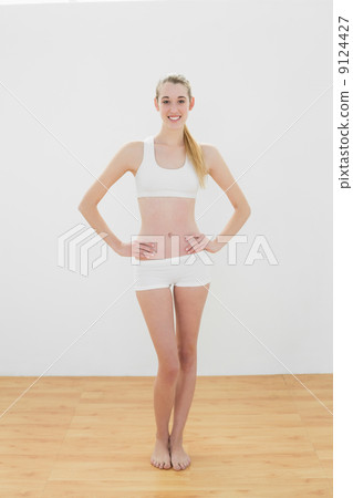 Happy attractive woman posing with her hands on hips smiling at Happy attractive woman posing with her hands on hips smiling at 9124427