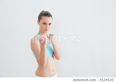Sporty fit woman clenching fists against wall Sporty fit woman clenching fists against wall 9124520