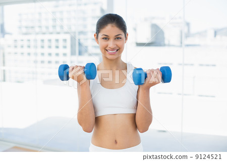 Woman exercising with dumbbells in fitness studio Woman exercising with dumbbells in fitness studio 9124521