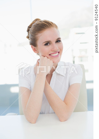 Smiling businesswoman sitting at office desk 9124540