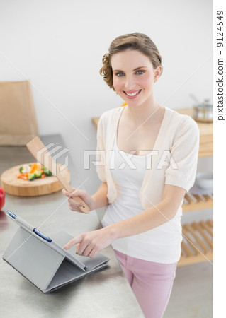 Content woman working with her tablet standing in the kitchen 9124549