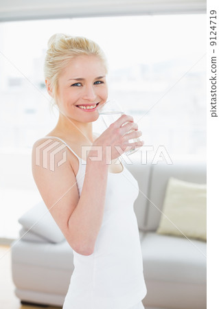 Portrait of a fit smiling woman drinking water at the gym 9124719