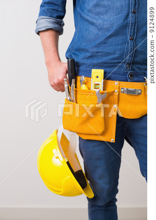 Mid section of a handyman with toolbelt and hard hat 9124899