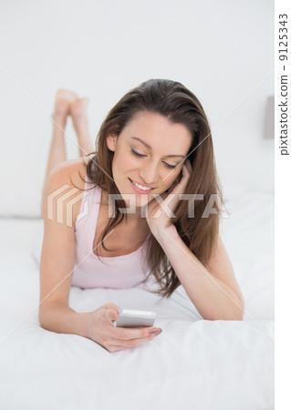 Relaxed happy woman looking at mobile phone in bed 9125343