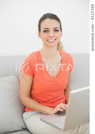 Smiling brunette woman working with her notebook looking at came 9125389