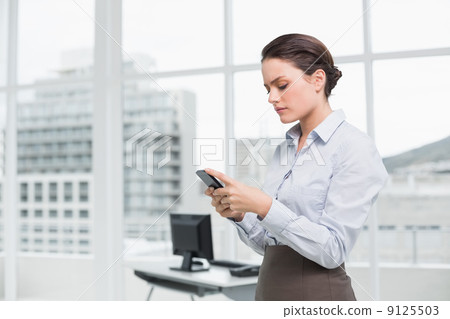 Businesswoman reading text message in office 9125503