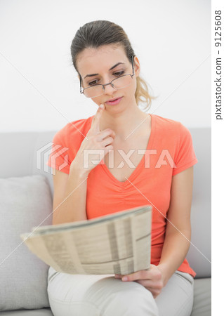 Attractive woman reading a magazine sitting on couch 9125608
