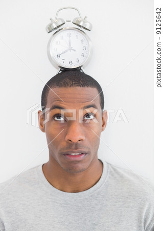 Close up of a man with an alarm clock on top of his head Close up of a man with an alarm clock on top of his head 9125642