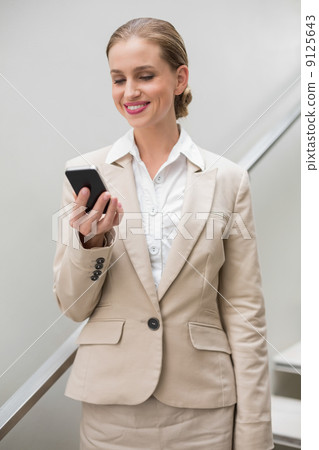 Smiling stylish businesswoman holding smartphone Smiling stylish businesswoman holding smartphone 9125643