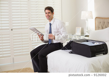 Businessman with coffee cup and newspaper by luggage at hotel ro 9126002