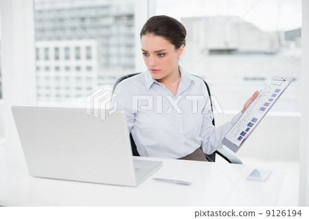 Businesswoman with graphs and laptop in office Businesswoman with graphs and laptop in office 9126194
