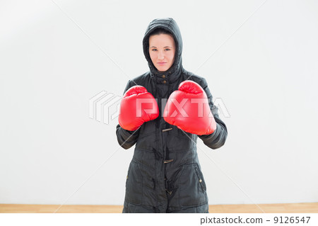 Tough woman in hooded jacket and red boxing gloves 9126547