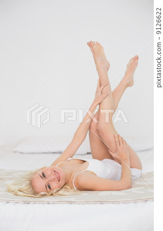 Smiling young woman in nightwear lying in bed 9126622