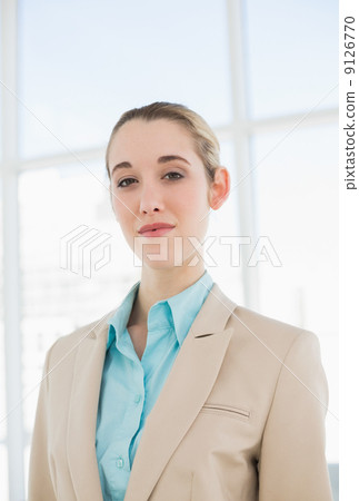 Lovely chic businesswoman posing seriously in her office 9126770