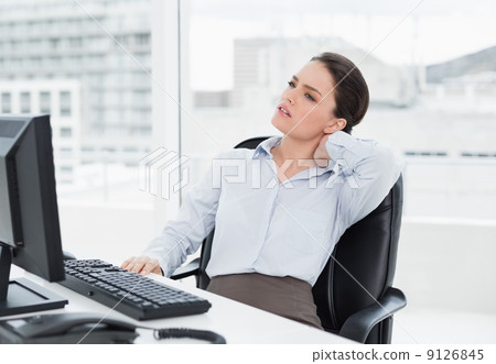 Businesswoman with neck pain sitting at desk 9126845