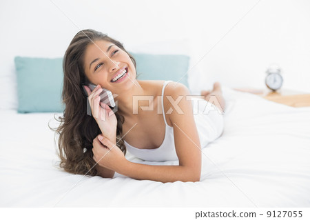 Cheerful woman using mobile phone in bed Cheerful woman using mobile phone in bed 9127055