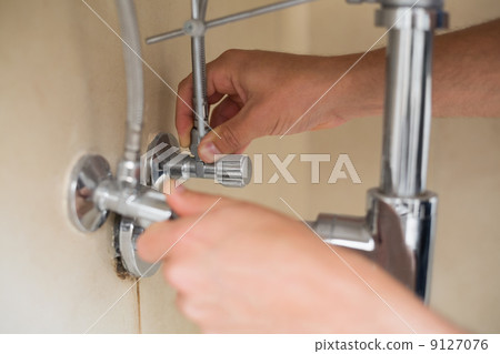 Close up of a plumber's hands and washbasin drain 9127076