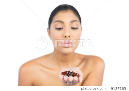 Unsmiling nude brunette holding tablets in open hand Unsmiling nude brunette holding tablets in open hand 9127163