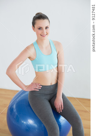 Fit woman sitting on exercise ball in fitness studio 9127481