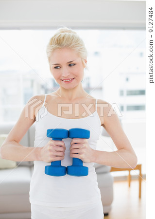 Thoughtful woman with dumbbells at fitness studio 9127484