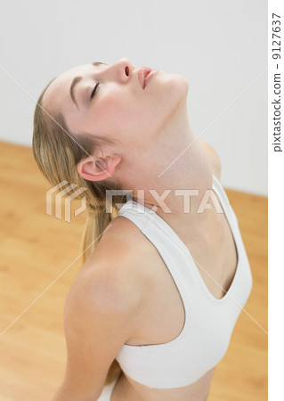 Lovely sporty woman stretching kneeling on floor in sports hall Lovely sporty woman stretching kneeling on floor in sports hall 9127637
