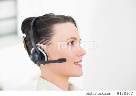 Close-up side view of a beautiful businesswoman using headset 9128167