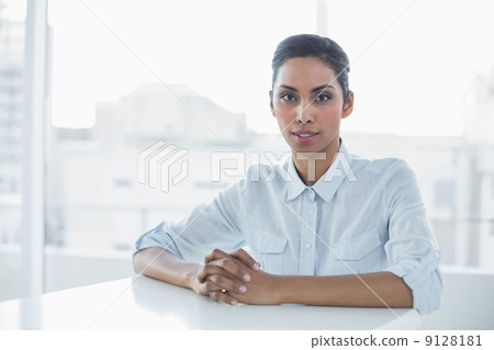 Stern chic businesswoman looking at camera while sitting at her Stern chic businesswoman looking at camera while sitting at her 9128181
