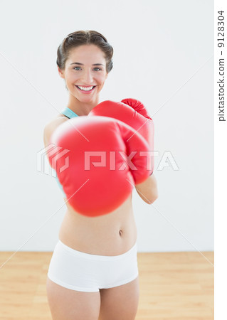 Beautiful woman in red boxing gloves at fitness studio Beautiful woman in red boxing gloves at fitness studio 9128304