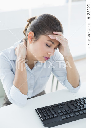 Businesswoman suffering from headache in front of laptop Businesswoman suffering from headache in front of laptop 9128305