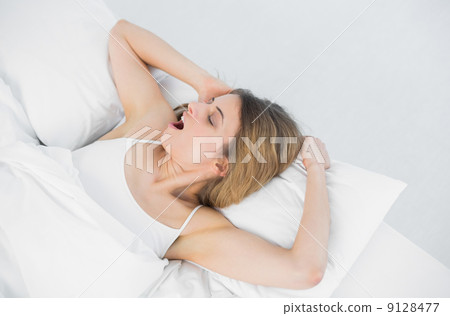 Lovely young woman yawning while lying on her bed 9128477