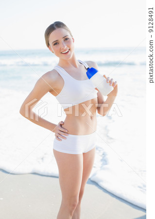 Smiling slender woman holding sports bottle Smiling slender woman holding sports bottle 9128491