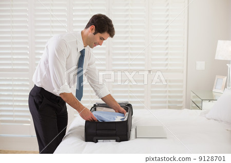 Businessman unpacking luggage at a hotel bedroom 9128701